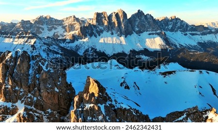 The snow-capped mountains, with their jagged peaks and valleys, create a breathtaking landscape. The sun's rays cast a warm glow on the snow, enhancing the scene's beauty.