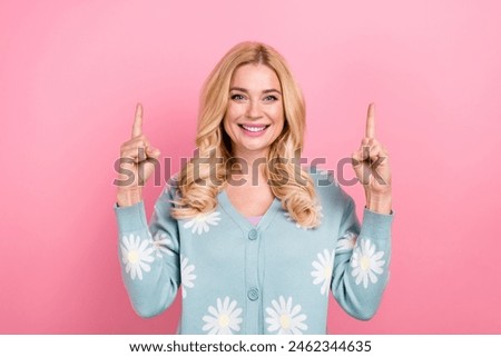Photo of good mood woman with wavy hairdo dressed print cardigan directing up at promo empty space isolated on pink color background