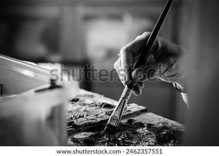 Woman's hand carrying paint brush on canvas black and white