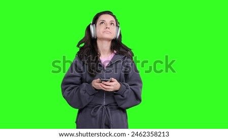 Sad woman wearing headphones and holding mobile phone on the chroma key