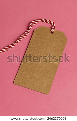 old cardboard clothing tag made from waste paper recycled eco-friendly item tag on pink background