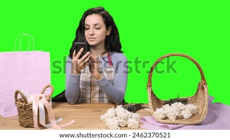 Smiling female florist showing phone screen at workshop on the chroma key