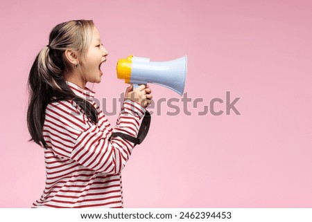 Side view of cute Asian girl using megaphone and making announcement, isolated on pink. Copy space. Shopping, sale concept. Advertisement