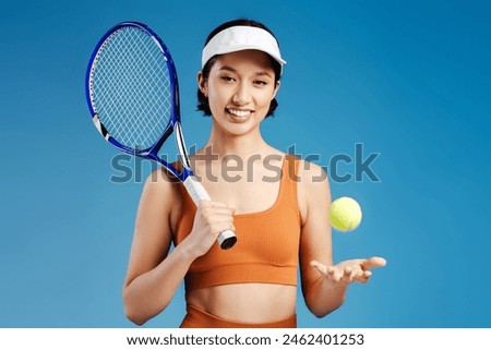 Happy smiling woman tennis player isolated on blue background posing with tennis racket and ball. Sport and hobby concept