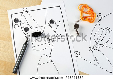 Scheme basketball game on sheet of paper and wooden table background