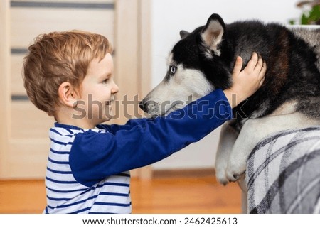 Young Boy Enjoying a Heartwarming Moment with His Husky Dog at Home Royalty-Free Stock Photo #2462425613
