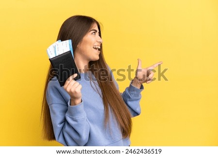 Young caucasian woman holding a passport isolated on yellow background pointing finger to the side and presenting a product