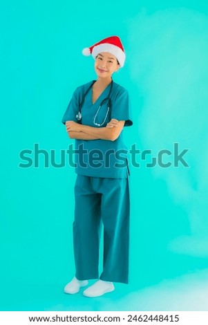 Portrait beautiful young asian doctor woman wear christmas hat with smile happy on blue isolated background