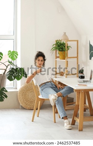 Young African-American woman drinking coffee at home office