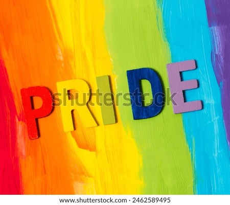 Colorful wooden letters spell 'pride' against a handpainted rainbow background Royalty-Free Stock Photo #2462589495
