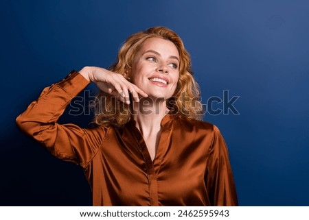 Photo of adorable lovely woman with wavy hair dressed silk shirt arm on cheek look empty space isolated on dark blue color background