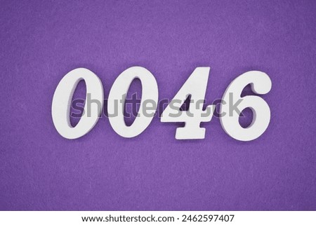 The number 0046 is made from white painted wood. Place it on a purple paper background.