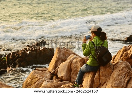 Young girl tourist taking pictures of the sea