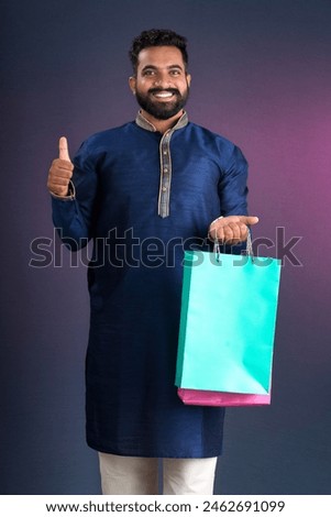 Indian traditional Young handsome man holding and posing with shopping bags on a dark background