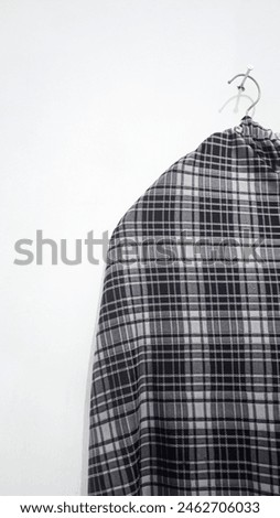 A close-up photo of a long skirt drying with small black and white checkered patterns on a white background portrait