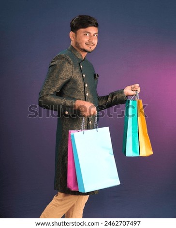 Indian traditional Young handsome man holding and posing with shopping bags on a dark background