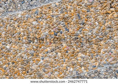 This is a photo of building wall decorated by small grey and yellow stones. It's close up view of colorful stones. It is view of texture of multicolored wall