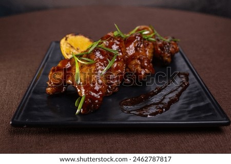 Grilled chicken wings in sweet tangy sauce with lemon slices. Perfect appetizer for a party or gathering. Delicious and flavorful dish. Royalty-Free Stock Photo #2462787817