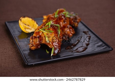 Grilled chicken wings in sweet tangy sauce with lemon slices. Perfect appetizer for a party or gathering. Delicious and flavorful dish. Royalty-Free Stock Photo #2462787829