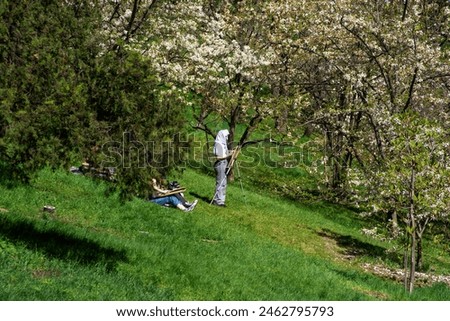 People paint pictures in the spring garden on a warm day