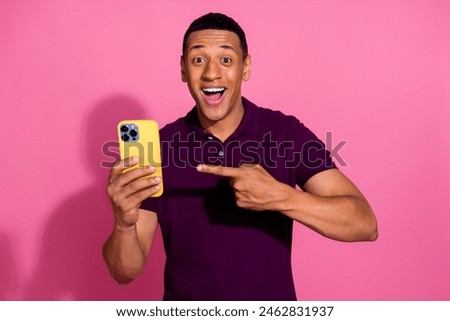 Photo portrait of nice young male hold point excited device dressed stylish violet garment isolated on pink color background