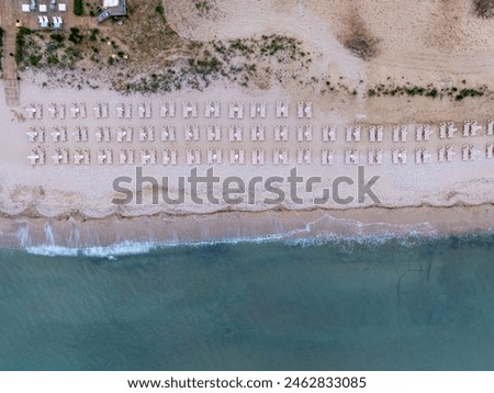 Top down view of a beach with sunbeds a with sand beach and clear blue water in Greece