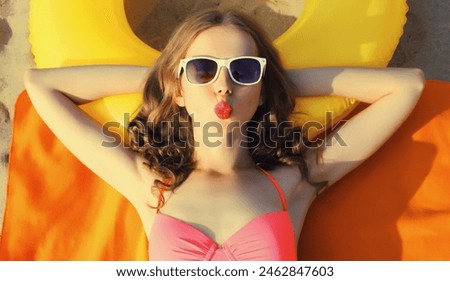 Summer vacation, happy relaxing young woman lying on sand on the beach with swimming inflatable ring