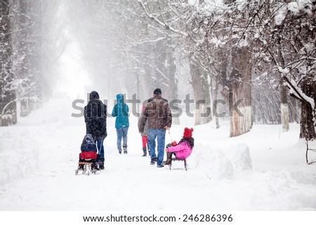 Snowing landscape in the park with people passing by with sledges