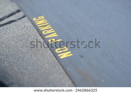 Yellow NO PARKING sign on asphalt 