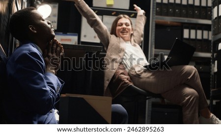 Diverse team of exhausted private investigators in incident room analyze evidence, review files, and conduct research to solve case. Two detectives feeling tired about criminal investigation reports. Royalty-Free Stock Photo #2462895263