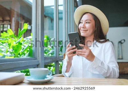 Portrait image of a beautiful young woman with hat holding and using mobile phone