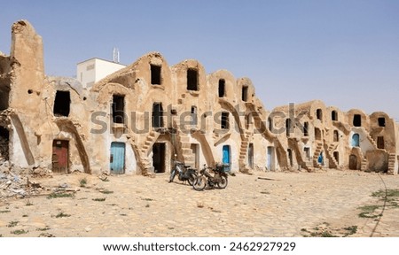 Bright sun illuminates dwellings and palm branches in village of Berbers. Gsar of Medenine, Berber, Tatahouine. Uncomplicated and simple village architecture of ancient Muslim tribes, Tunisian Berbers Royalty-Free Stock Photo #2462927929