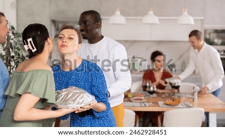 Happy middle-aged pair welcoming their guests during small gathering with close friends at home