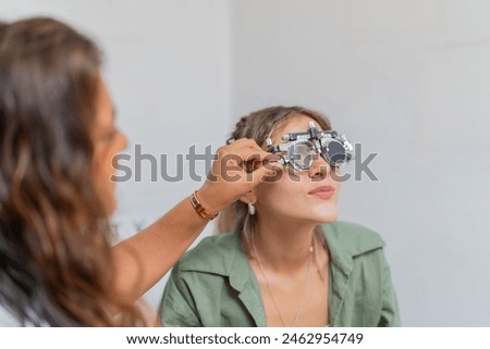 Young woman checking vision in ophthalmology clinic using an optometrist test frame
