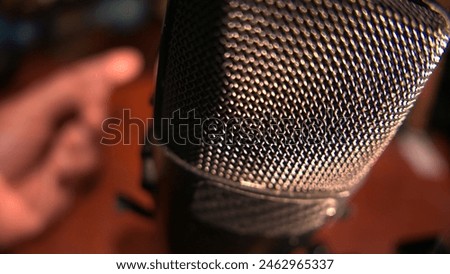 POV of a person gesturing and speaking into a microphone. A man recording a podcast episode in a soundproof studio. Person recording audio for podcasts. Close-up shot of a big digital microphone.  