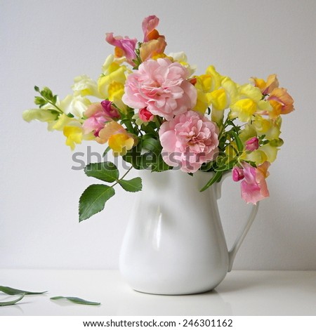 Bouquet of snapdragon flowers and roses in a vase. Floral decoration with antirrhinum majus and roses.