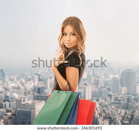 people, holidays and sale concept - young happy woman with shopping bags over city background