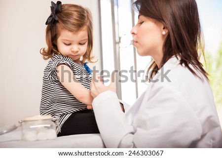 Profile view of a pretty little girl getting a vaccination at a doctor's office