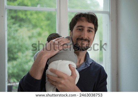 A father beams with joy as he cradles his newborn baby, highlighting a heartwarming moment of love and connection in a serene home environment. Royalty-Free Stock Photo #2463038753