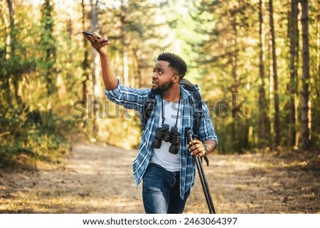 Young hiker is searching signal  for mobile phone in nature.