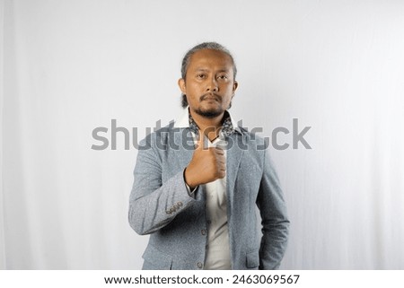 Asian curly businessman standing looking at camera while giving thumbs up, approval, business advertisement and copy space, isolated on white background.