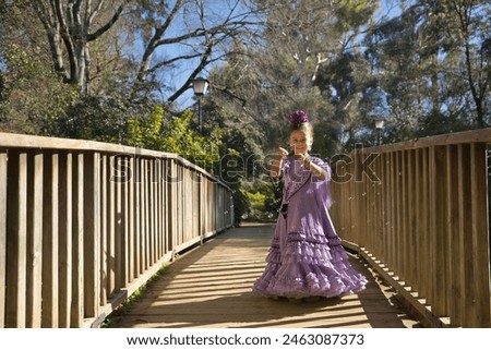 A girl dancing flamenco, playing with soap bubbles, in typical flamenco dress, on a wooden bridge. Concept dance, flamenco, typical Spanish, Seville, Spain. Royalty-Free Stock Photo #2463087373
