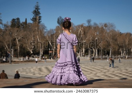 Girl dancing flamenco, posing on her back, in typical flamenco dress on a bridge in a beautiful square in Seville. Dance concept, flamenco, typical Spanish, Seville, Spain. Royalty-Free Stock Photo #2463087375