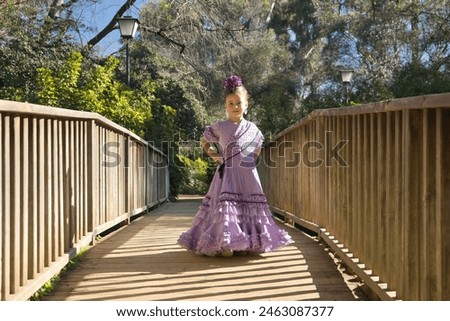Girl dancing flamenco, posing looking at the camera, in typical flamenco dress, on a wooden bridge. Concept dance, flamenco, typical Spanish, Seville, Spain. Royalty-Free Stock Photo #2463087377
