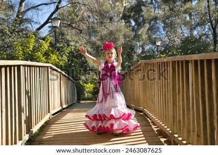 A girl dancing flamenco, playing with soap bubbles, in typical flamenco dress, on a wooden bridge. Concept dance, flamenco, typical Spanish, Seville, Spain. Royalty-Free Stock Photo #2463087625