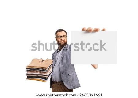 Bearded man with a pile of folded clothes showing a blank card isolated on a white background