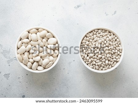 Two bowl plates with large and small raw dry beans on kitchen table. Royalty-Free Stock Photo #2463095599