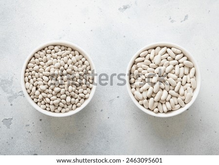 Two bowl plates with medium and small raw dry beans on kitchen table. Royalty-Free Stock Photo #2463095601