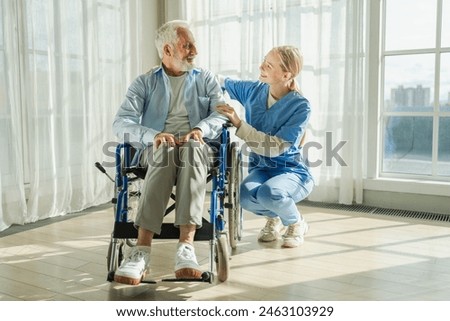 Help support retirement healthcare. Nurse helping old man in wheelchair. Patient and woman in nursing home for medical caregiver. Nurse taking care of paralyzed man in chair for people with disability Royalty-Free Stock Photo #2463103929