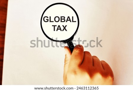 Magnifying glass over the pile of money with the text "Global Tax". Concept of the new European tax.